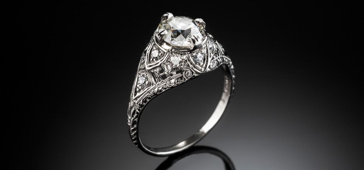 An Edwardian platinum and solitaire diamond ring in a diamond embellished domed mount