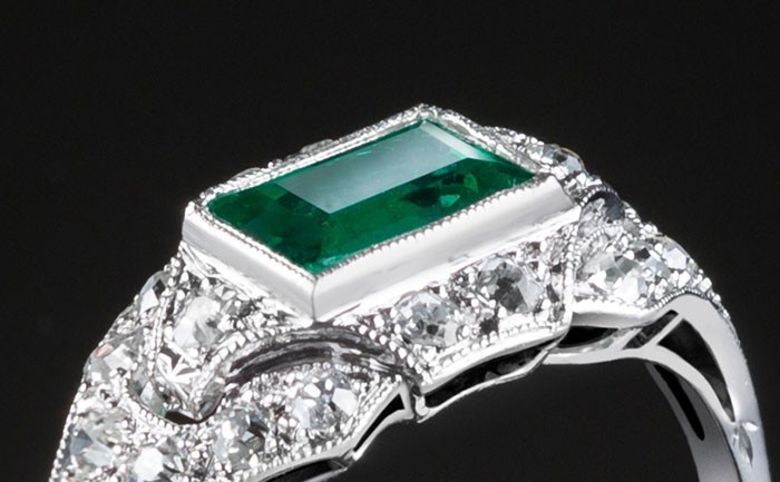 An Art Deco step cut emerald and diamond ring