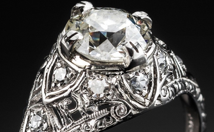 Detail of an Edwardian platinum and solitaire diamond ring in a diamond embellished domed mount